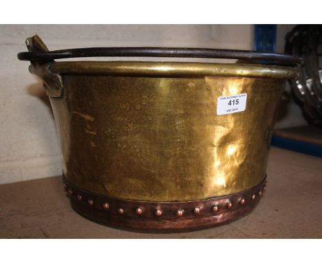 A brass and copper planter with a handle 