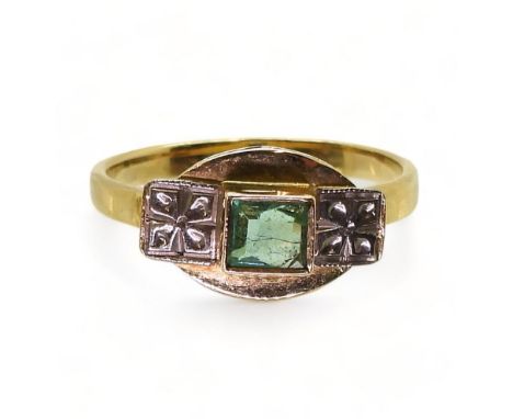 AN EMERALD ART DECO RING made in bright yellow metal with white metal Deco flower details, the emerald is step cut and approx