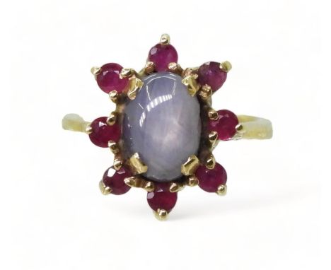 A RUBY AND STAR SAPPHIRE RING set in bright yellow metal stamped 750, the centre of the flower cluster is a pale blue star sa