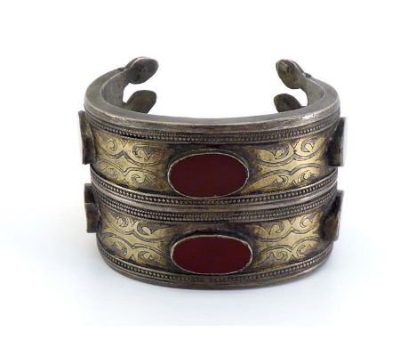 A Middle Eastern, white metal and alloy cuff bangle, set with two rows of oval carnelian tablets, 58mm inner diameter, 154.7g