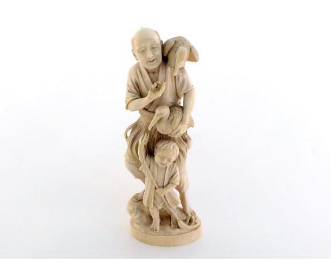 A very elaborately carved Japanese Meiji period ivory okimono of a cormorant fisherman with a child, the well carved figure i