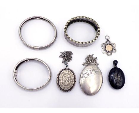 A group of Victorian silver and white metal jewellery, including three hinged bangles, two lockets, each engraved, one with t