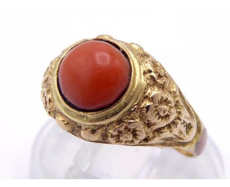 A 19th century coral ring, the small circular coral cabochon 6.4mm, with floral chased shoulders, mounted in yellow metal (te