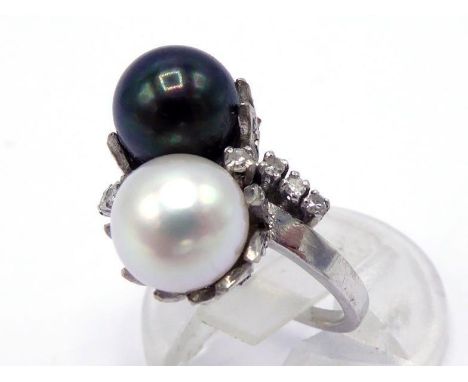 A two colour pearl and diamond ring, the cross over mount with an 8.2mm black and white pearl, a trail of small brilliants be