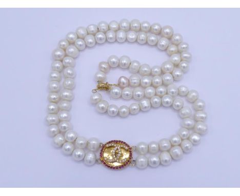 A two strand freshwater cultured pearl necklace, composed of uniform (approx. 10mm) circled pearls, to an off-centre yellow m