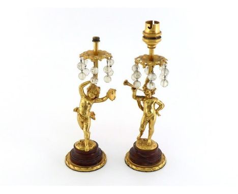After Auguste Moreau. A pair of ormolu electric table lamps in the form of naked children, one playing a horn, the other a ta