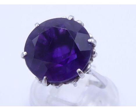 An amethyst dress ring, the large round cut stone 13.5 x 9.3mm, claw set above a white metal shank, stamped '750', finger siz