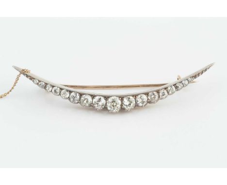 A late Victorian/Edwardian diamond crescent brooch, designed as a line of graduated old-cut diamonds, above a scalloped galle