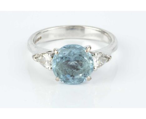 An aquamarine and diamond three stone ring, the circular mixed-cut aquamarine claw set between two pear-shaped brilliant-cut 