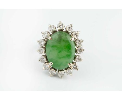 A jade and diamond cluster ring, the oval jadeite cabochon claw set within a border of round brilliant-cut diamonds, white pr