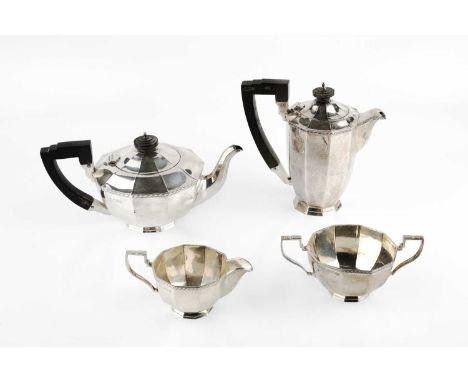 A silver four piece tea service, of octagonal faceted form, the tea pot and hot water pot with ebonised handles and knops, by