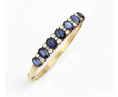 A synthetic sapphire and diamond line bangle, of hinged oval hollow form, the graduated oval mixed-cut synthetic sapphires sp