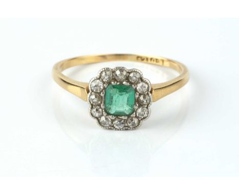 An emerald and diamond cluster ring, the rectangular step-cut emerald with canted corners, bordered by millegrain set single-