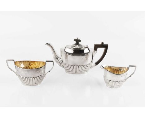 A late Victorian silver bachelor's three piece tea service, of oval half-lobed form, the tea pot with ebonised handle and kno