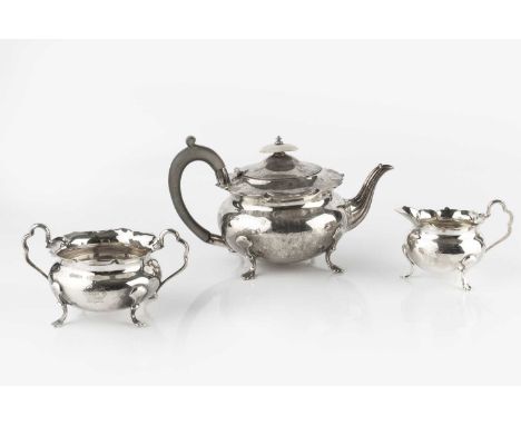 An Edwardian silver three piece tea service, of squat circular form with shaped edges, the tea pot with wooden handle and kno