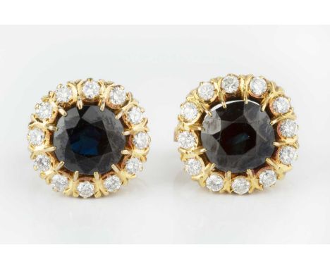 A pair of sapphire and diamond cluster ear clips, each centred with a cushion-shaped mixed-cut sapphire in claw setting, bord