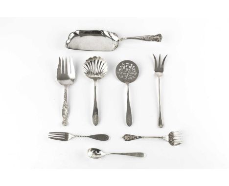 A collection of American silver flatware, comprising a scalloped ladle, five table spoons, a crumber, a pierced serving slice