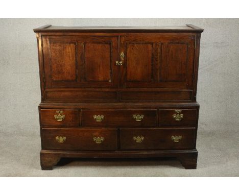 A mid 18th century oak Welsh press cabinet of low proportions, the upper section with two panelled doors over three shprt dra