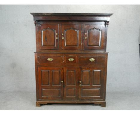 An 18th century oak court cupboard type estate cabinet, with three cupboard doors, the central door enclosing drawers and pig