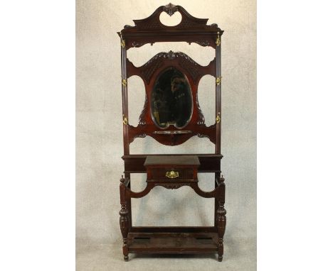 A late Victorian Chippendale style walnut hall stand, the scrolling pediment with blind fretwork detail, over a shaped bevell