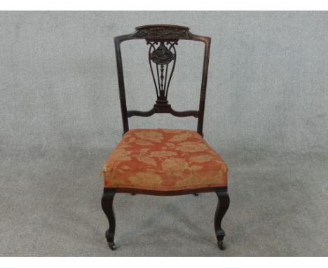 A late Victorian walnut side chair, with an ornately carved and pierced back splat, the seat upholstered in floral fabric in 