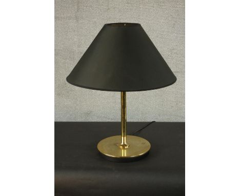 A contemporary brass table lamp, with a slender stem and a circular base, with a black shade. H.60 Dia.59cm. 