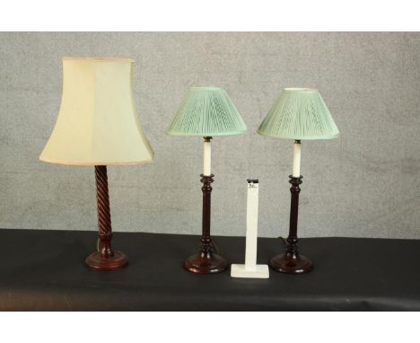 A pair of mahogany candlestick design table lamps with green silk shades along with another example with turned barley twist 