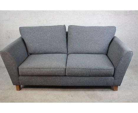 A contemporary two seater sofa upholstered in grey fabric, with loose back and seat cushions, on block feet. H.85 W.185 D.93c