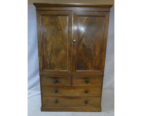 A mid 19th century figured mahogany linen press with panel doors enclosing linen slides above two short and two long drawers 