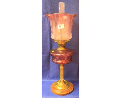 19th Century brass double burner oil lamp with writhen cranberry glass reservoir on brass pedestal with stepped wooden base, 