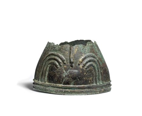  A fragmentary Urartian bronze helmet  Circa 9th-8th Century B.C.The moulded raised lions head arches flanked by partially pr