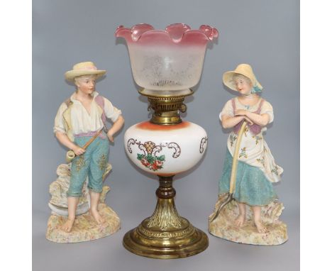 A pair of French coloured biscuit figures and an oil lamp