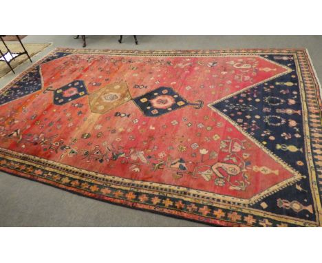 A Luri carpet, West Iran, the shaded red field of tribal devices around three stepped medallions, enclosed by narrow moss gre