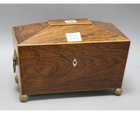A Regency rosewood sarcophagus shaped tea caddy, the lifting top enclosing two covered compartments, inlaid with boxwood stri