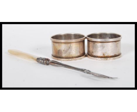 A pair of silver hallmarked napkin rings along with a silver plate toasting fork having scrolled detailing and a mother of pe
