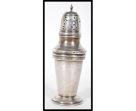 A silver hallmarked sugar shaker of tapering cylindrical form being raised on a stepped round base with a finial to the top. 