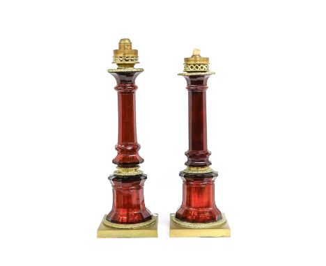 A Near Pair of Brass-Mounted Ruby Glass Candlestands, late 19th century, with spring-loaded candle holders on panelled column