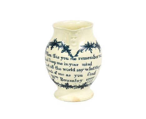 A Documentary Creamware Mask Jug, dated 1777, of ovoid form with entwined strap handle, inscribed in underglaze blue When thi