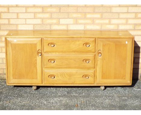 An Ercol sideboard having a central section of three drawers flanked by cupboards, approximately 68 cm x 155 cm x 45 cm.