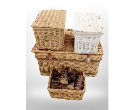 A wicker hamper and three baskets (one containing copper birch logs and pine cones)