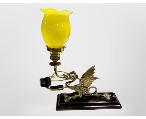 A brass table lamp in the form of a dragon on lacquered plinth with yellow glass shade, height 37 cm