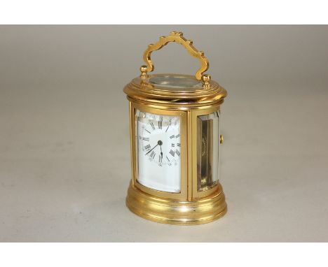 A Drocourt miniature brass carriage clock, oval form with glass panels and white enamel dial with Roman numerals, 10cm high