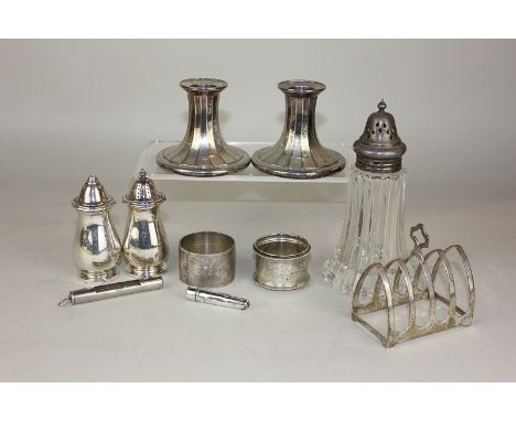 A silver toast rack, two silver napkin rings, cheroot holder case, egg timer, plated candlesticks, plated peppers, plated sug