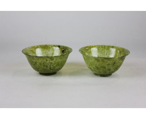 A pair of Chinese green jade bowls with flared rims on short bases, 10cm diameter