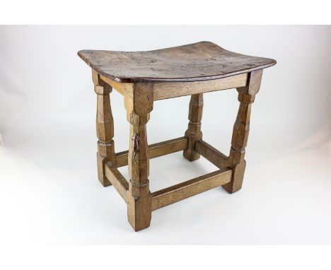 A Robert Mouseman Thompson oak stool with curved top and octagonal legs separated by four stretchers, 40cm by 27cm