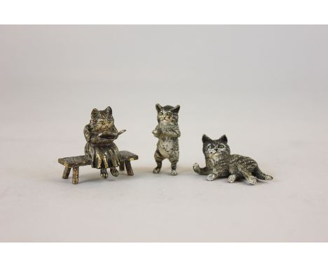 Three Austrian cold painted bronzes of cats, one sitting on a bench reading a book, one lying down and one standing on its hi