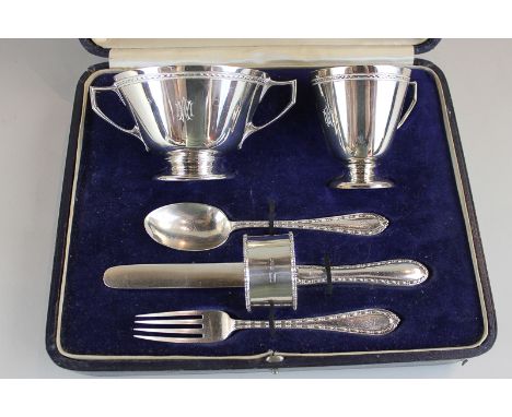 A George V cased silver christening set comprising two-handled bowl, christening mug, knife, fork, spoon and napkin ring, mak