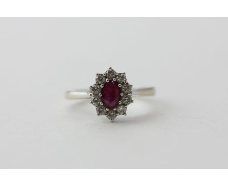 A ruby and diamond cluster ring in 18ct white gold, the oval cut ruby within a border of ten brilliant cut diamonds