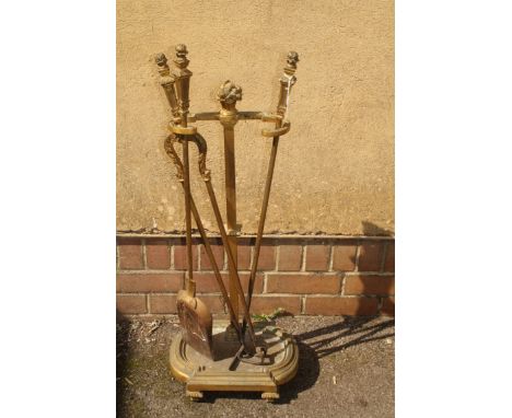 A 19th century brass and iron three piece companion set, the stand and tools with flowering basket finials and neo-classical 