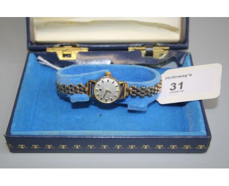 Tissot A lady's 9ct gold wristwatch, circular champagne dial, baron numerals, manual movement to a 9ct gold gatelink bracelet